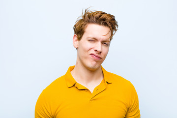 young red head man looking happy and friendly, smiling and winking an eye at you with a positive...