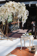 wedding decor: a large garland of white flowers and crystals, a decorative table with various objects