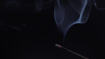 Burning incense stick on black background, close-up. Copy space for text.