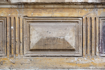 A stone bas-relief decoration in the form of a rectangle on the wall of a dilapidated building.