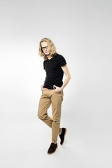 A young handsome guy spectacled with  long blonde hair, isolated on a light background.