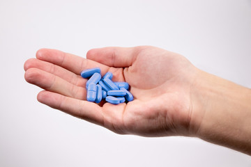 Blue pills in man`s hand on white background