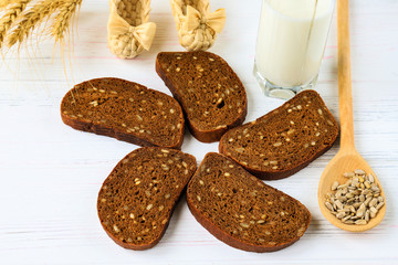 Rustic breakfast on a wooden background - sliced bread with seeds, seeds on a spoon, ears of wheat. wicker shoes