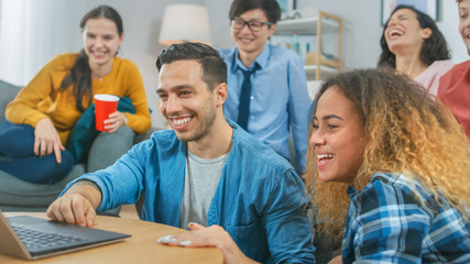 Diverse Group of Friends Use Laptop in the Living Room. Happy Beautiful Girls and Guys Live Streaming or Watching Content. They Have Fun and Laugh.