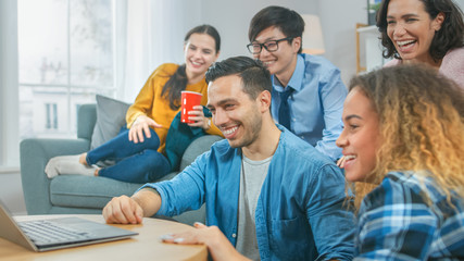 Diverse Group of Friends Use Laptop in the Living Room. Happy Beautiful Girls and Guys Live Streaming or Watching Content. They Have Fun and Laugh.