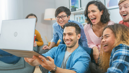 Diverse Group of Friends Use Laptop in the Living Room. Happy Beautiful Girls and Guys Doing Live Streaming. They Have Fun and Laugh.