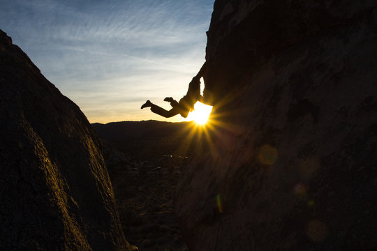 Silhouette of a climber with feet in the air and a starburst.