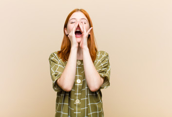 young red head pretty woman feeling happy, excited and positive, giving a big shout out with hands next to mouth, calling out