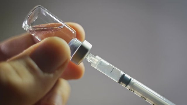 Doctor with medical syringe in hands, getting ready for injection