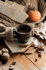 Autumn, fall leaves, a hot steaming cup of coffee and a warm sweater on a wooden table background. Seasonal, morning coffee, sunday relaxation and still life concept.