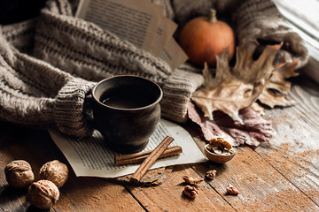 Autumn, fall leaves, a hot steaming cup of coffee and a warm sweater on a wooden table background. Seasonal, morning coffee, sunday relaxation and still life concept.
