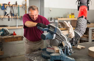 Carpenter cutting a wooden workpiece on an electical circular saw