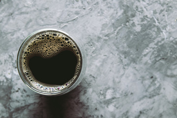 large transparent glass filled with of aromatic Turkish coffee photographed on the gray background