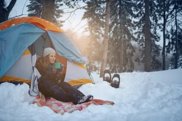 Gordijnen Zelfverzekerde solo-vrouwenreiziger die door een altijd groen winterbos in Canada kampeert © AYAimages