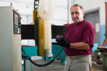 Elderly master manages 3d machine in factory