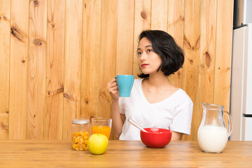 Asian young woman having breakfast holding a cup of coffee