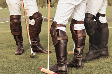 A group of male professional equestrian polo players. Leather brown high boots, protective knuckles, hammer and whiplash in the hands of riders