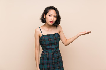 Obraz premium Asian young woman over isolated yellow wall making doubts gesture