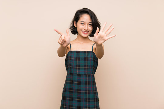 Asian young woman over isolated yellow wall counting seven with fingers