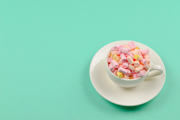 Cup with marshmallow on a green background. Copy space.