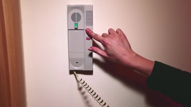 Using house intercom system. Woman using the intercom in the apartment