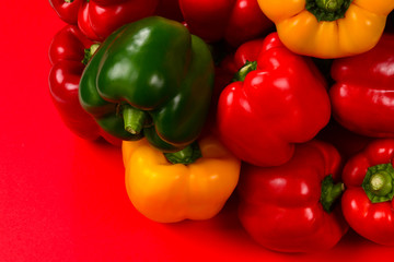Fresh red, yelow, green bell pepper on a red background.
