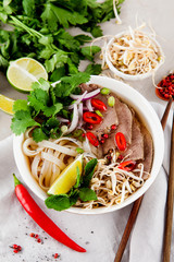 Vietnamese Pho Noodle Soup on light table. Beef with Chilli, Basil, Rice Noodles, Bean Shoots showing noodles