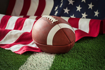 Football on field with stripe and American flag behind