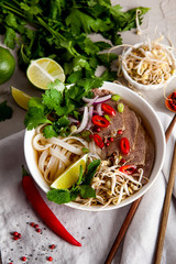 Vietnamese Pho Noodle Soup on light table. Beef with Chilli, Basil, Rice Noodles, Bean Shoots showing noodles
