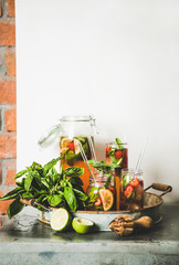 Fresh homemade strawberry and basil lemonade or ice tea in glass tumblers with eco-friendly plastic-free straws on rustic metal tray, white wall at background, copy space. Summer refreshing soft drink