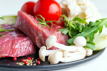 Raw beef steak with fresh vegetables in a pan on a marble background, top view