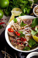 Pho Noodle Soup on dark table. Beef with Chilli, Basil, Rice Noodles, Bean Shoots showing noodles