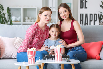 Happy lesbian couple with little daughter at home