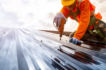 Construction worker install new roof,Roofing tools,Electric drill used on new roofs with Metal Sheet. - obrazy, fototapety, plakaty