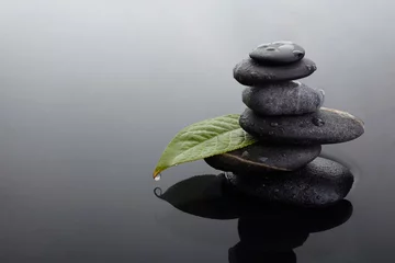 Selbstklebende Fototapeten Zen Zen stones in balanced pile and green leaf with water drops in water  © vetre
