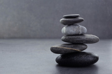 zen stones in balanced pile on dark grey background