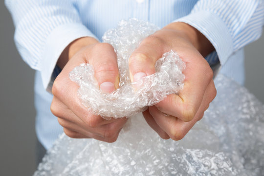 Female hands popping the bubbles of bubble wrap. Stress relief, anger management