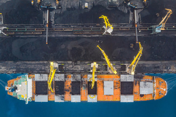 Loading coal anthracite mining in port on cargo tanker ship with crane bucket of train. Aerial top...