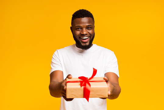 Cheerful African American Man Offering Gift Box To Camera