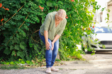 Mature woman suffering from pain in knee outdoors