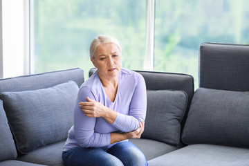 Mature woman suffering from pain in shoulder at home