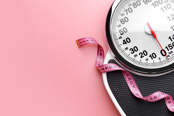 Scales and measuring tape on color background. Weight loss concept