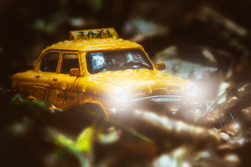 A yellow taxi car in drops of rain breaks through the autumn mist with its headlights on,...
