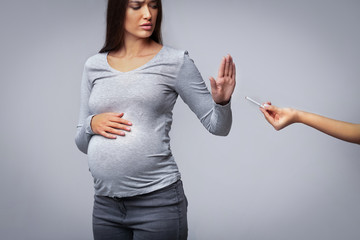 Pregnant Girl Refusing To Take Cigarette Gesturing Stop, Gray Background