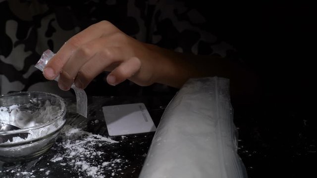 White drug powder packaged in plastic bags. Hands of a minor child