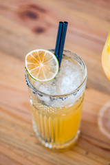 Top view of an orange cocktail in a tall glass on wooden background.
