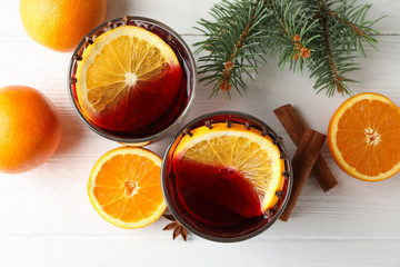 Glasses of tasty mulled wine with orange on white wooden background, top view