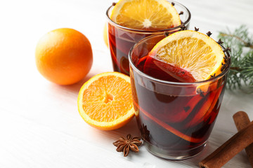 Glasses of tasty mulled wine with orange on white wooden background, close up