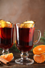 Glasses of tasty mulled wine with orange on wooden background, space for text