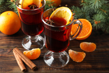 Glasses of tasty mulled wine with orange on wooden background, close up